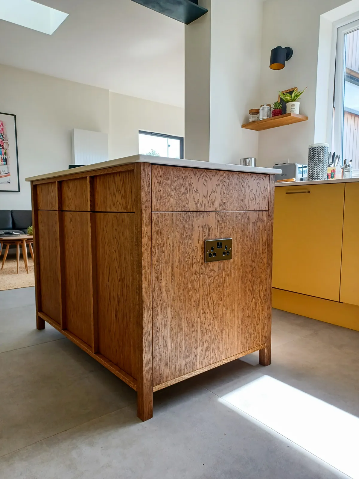 End of a bespoke oak kitchen island showing panelled sides and an integrated socket