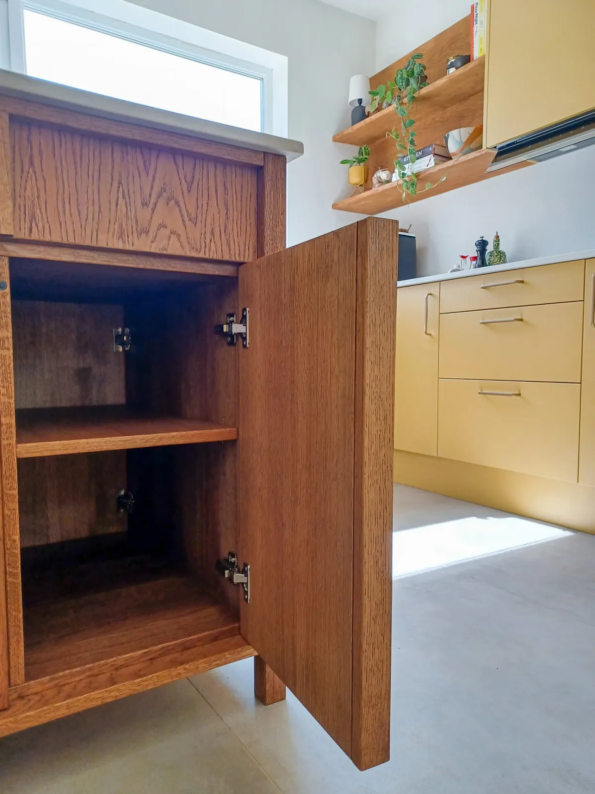 Open solid oak cupboard showing shelving, brass hinges and internal construction