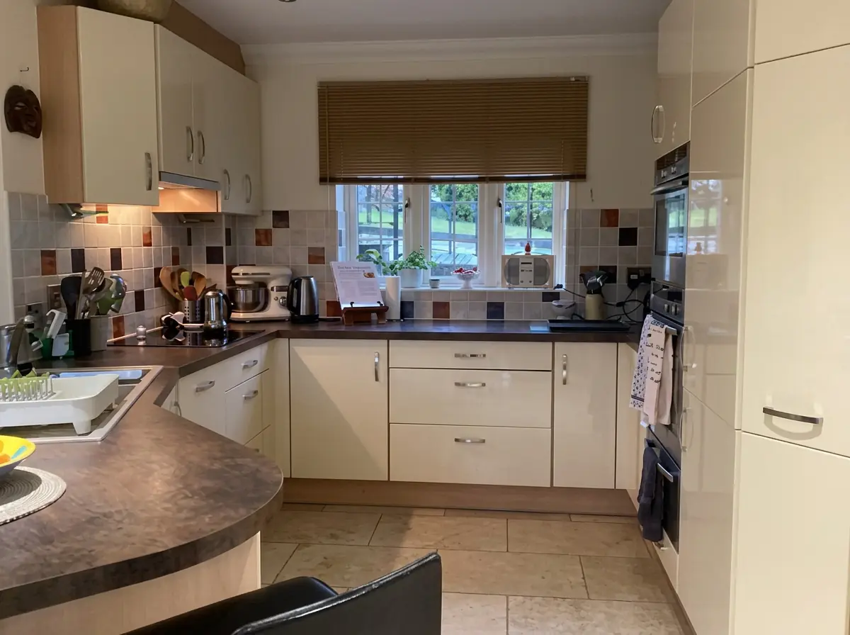 Cream kitchen with dated tiled splashback and dark laminate worktops before the refresh