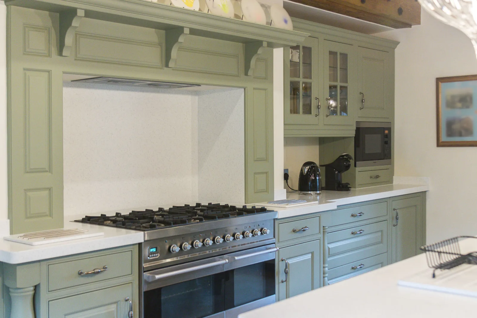The finished kitchen with sprayed pale green cabinetry, a range cooker and a classic mantel